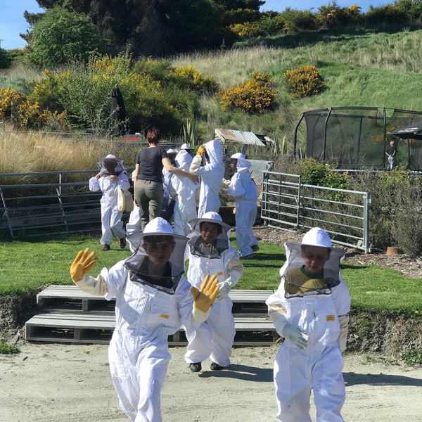 Adult and children in beekeeping suits